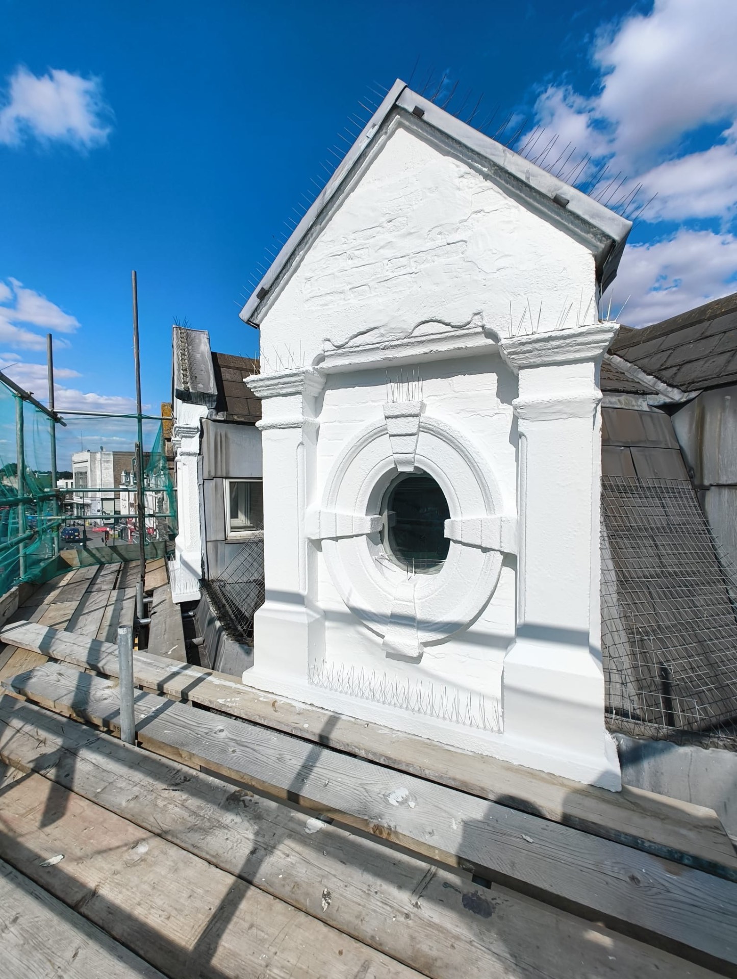 Restored roof dormer with a round porthole window and new bird spikes