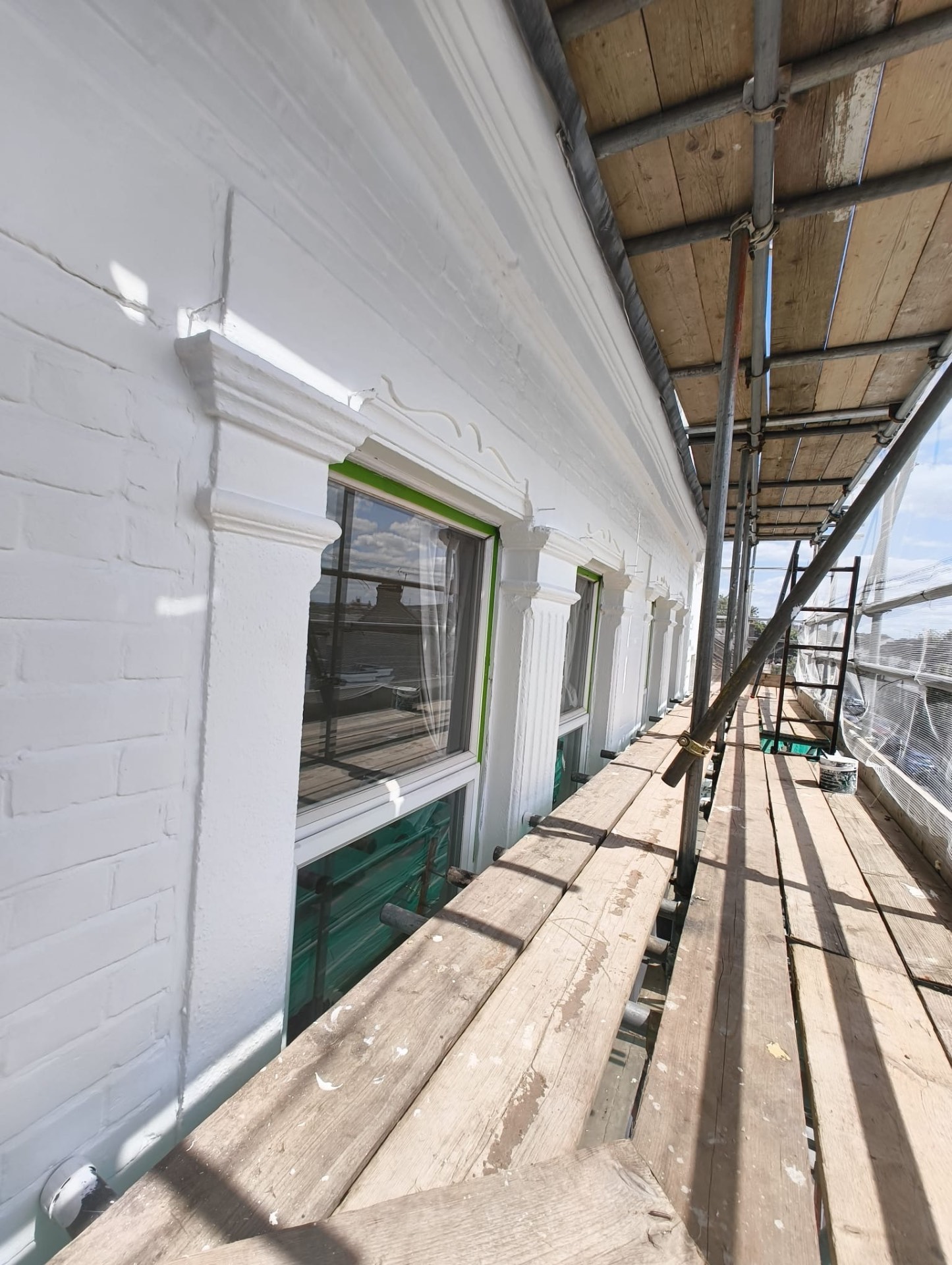Run of repaired window heads and pilasters newly painted from the scaffold