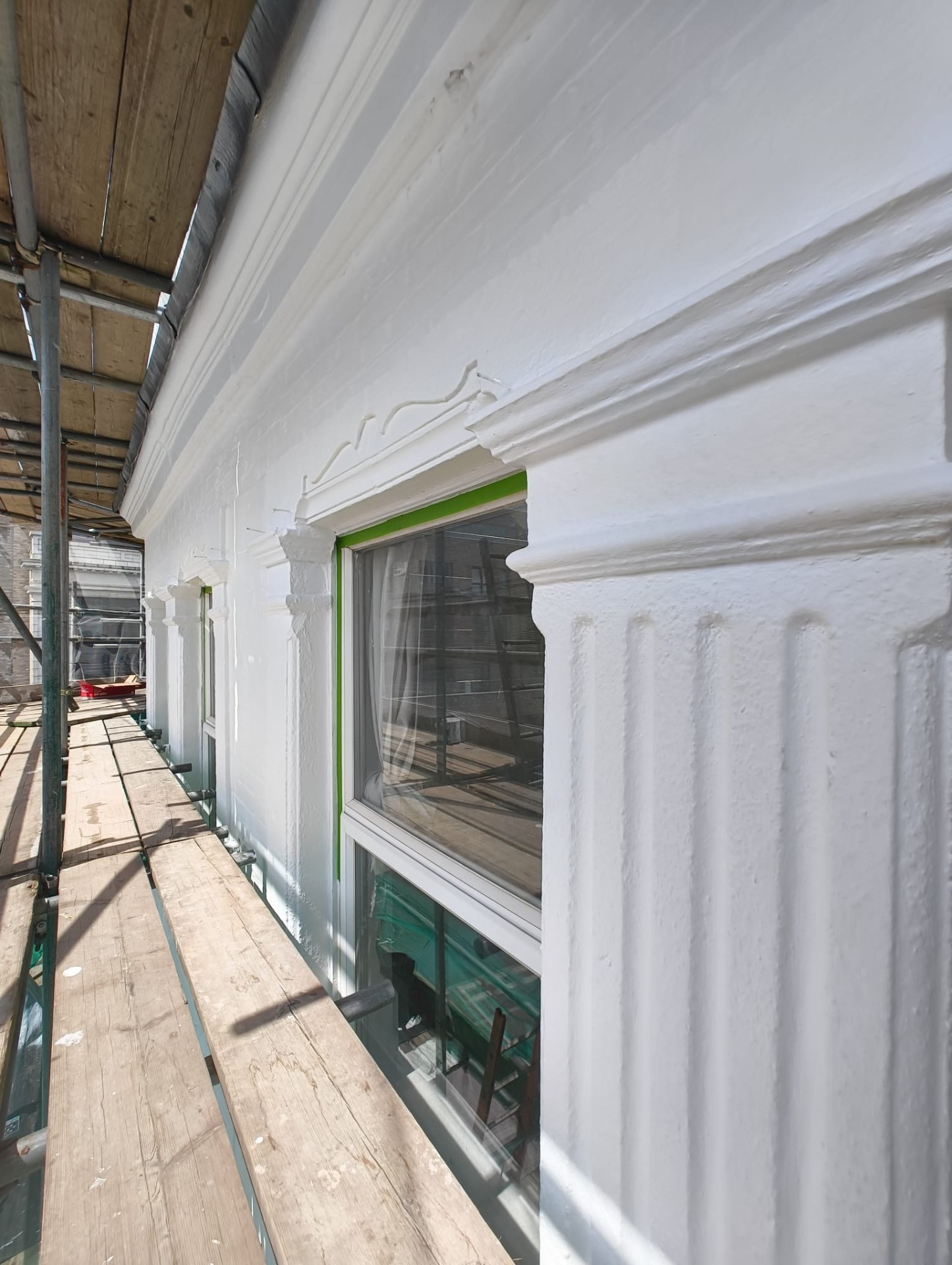 Repaired cornice and fluted pilaster detail with window frames masked off