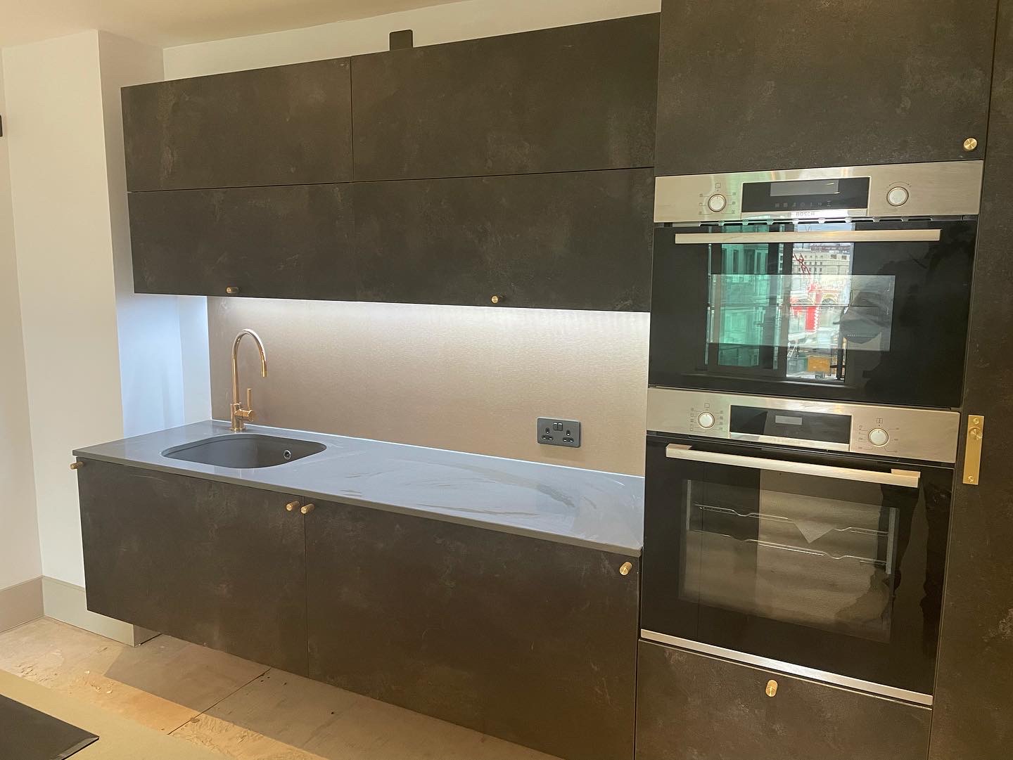 New full-height dark kitchen cabinetry with integrated appliances
