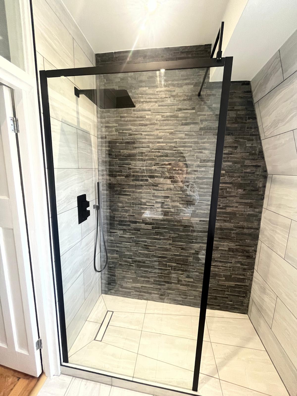 Black framed glass shower screen and full height tiling