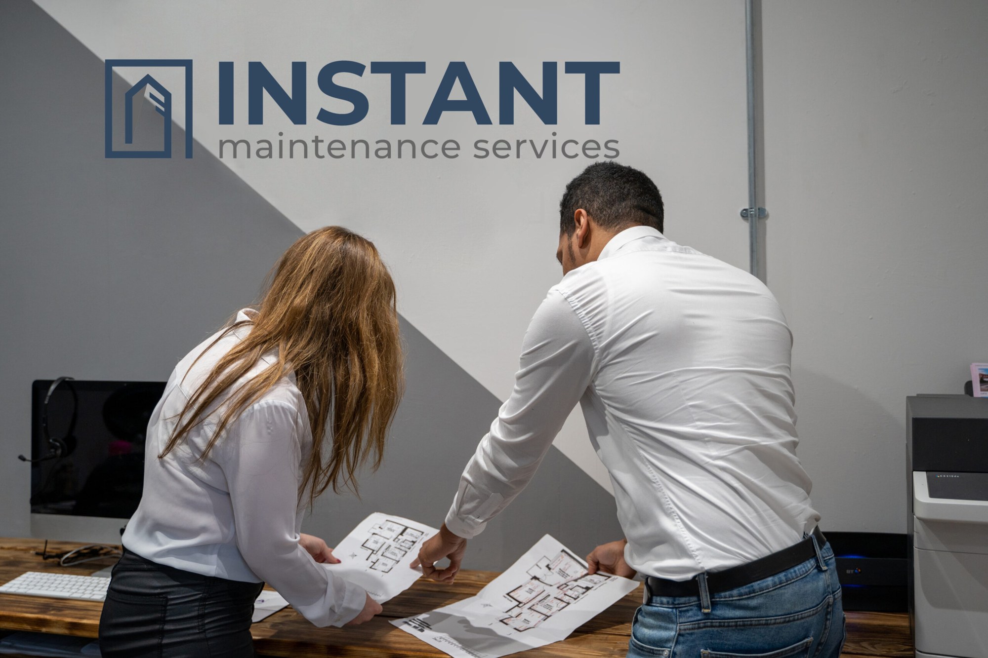 IMS estimating team reviewing drawings at the London office beneath the branded wall sign
