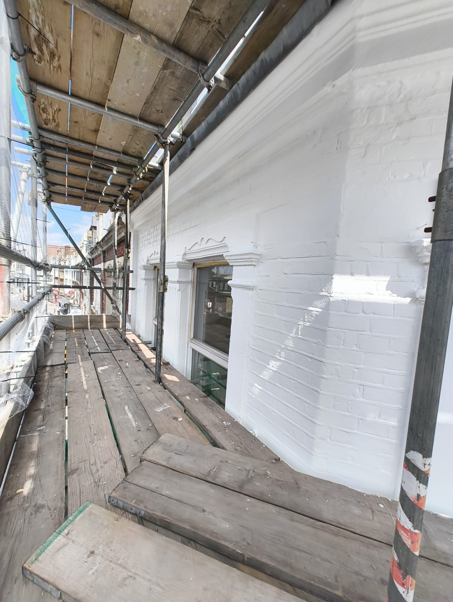 Side return brickwork repainted in white above the shop fronts