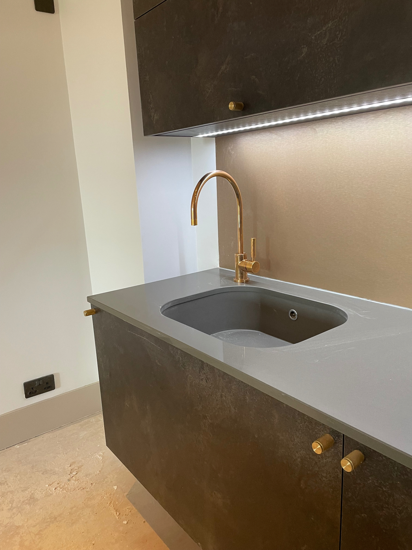 Undermounted sink with brushed brass tap and illuminated splashback