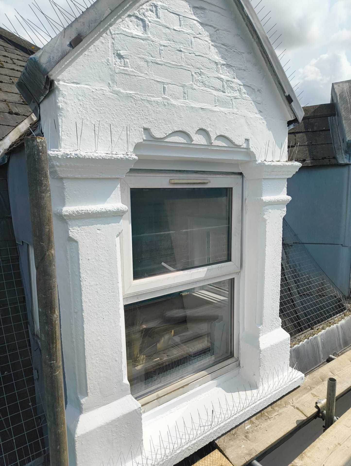 Repaired dormer window surround and pediment finished in white