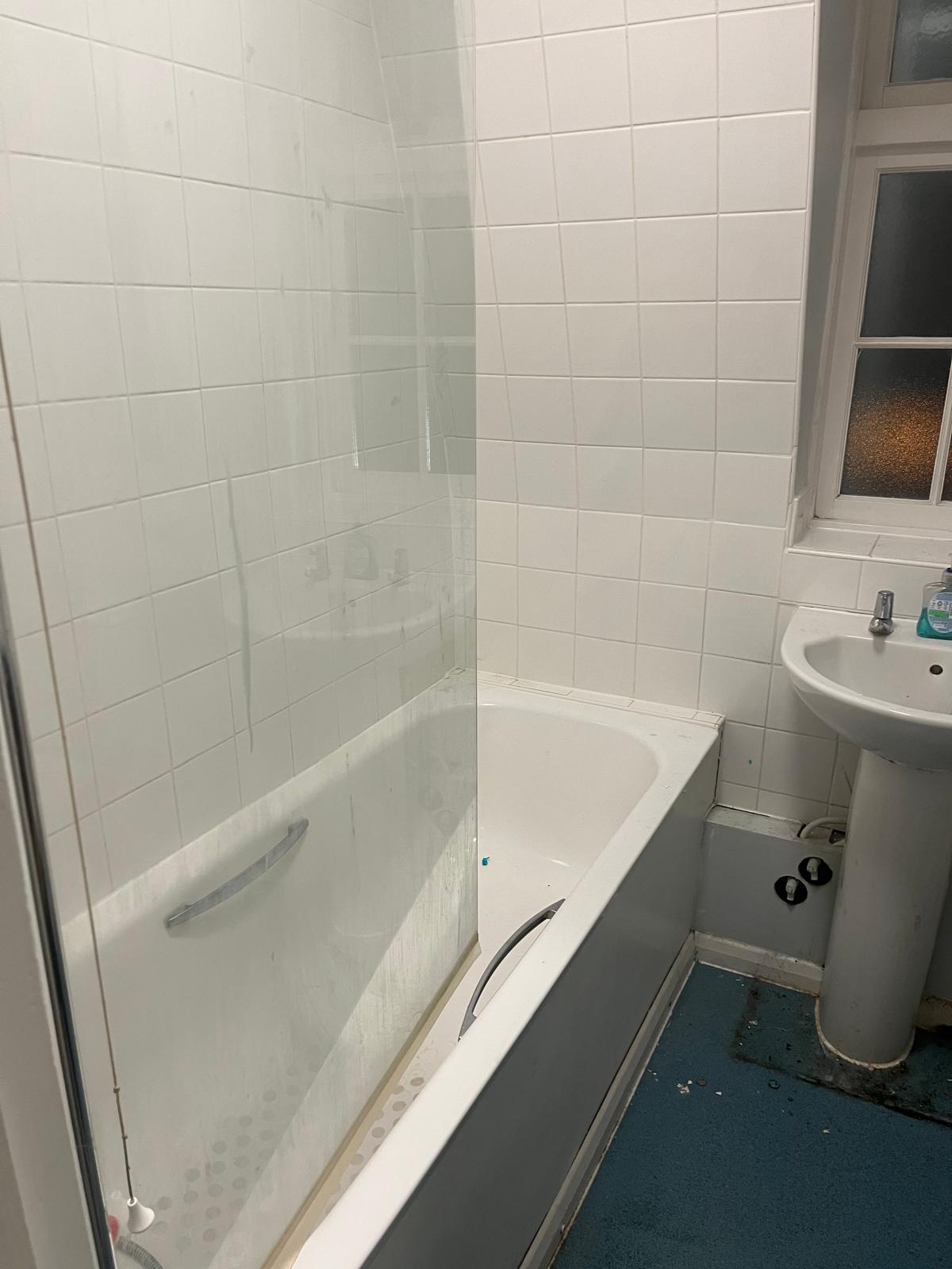 Original bathroom with a panelled bath and white wall tiles before works